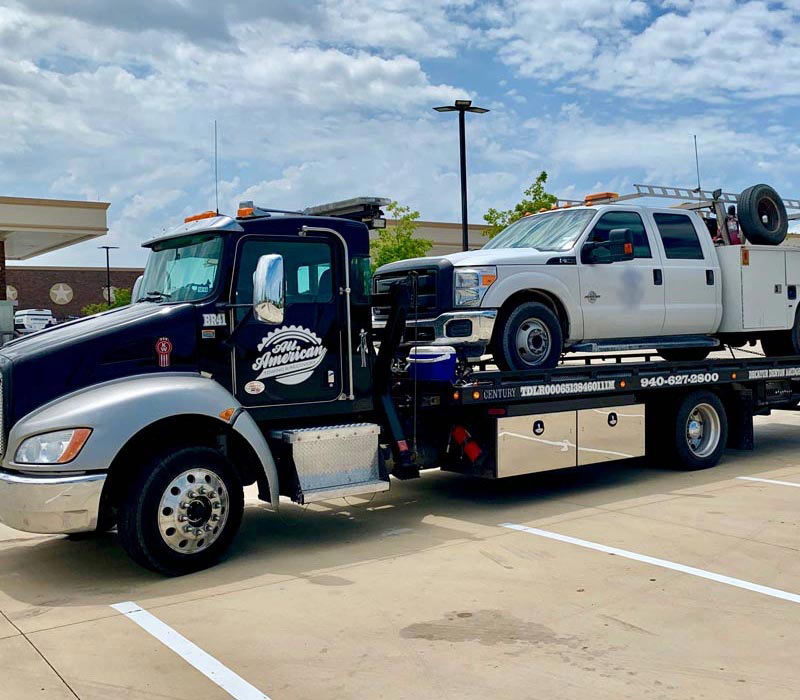 Flatbed-Tow-Truck-Transporting-a-White-Pickup-Truck-Justin-Texas-All-American-Towing Flatbed Tow Truck Transporting a White Pickup Truck Justin Texas All American Towing