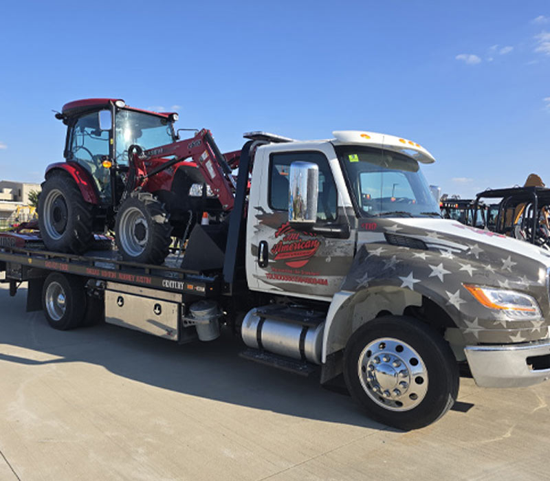 Flatbed-Tow-Truck-Transporting-a-tractor-in-Justin-Texas-All-American-Towing Flatbed Tow Truck Transporting a tractor in Justin Texas All American Towing